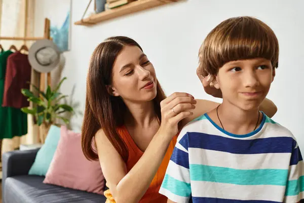 A mother lovingly assists her son with hearing impairment while seated in their cozy living room. — Stock Photo