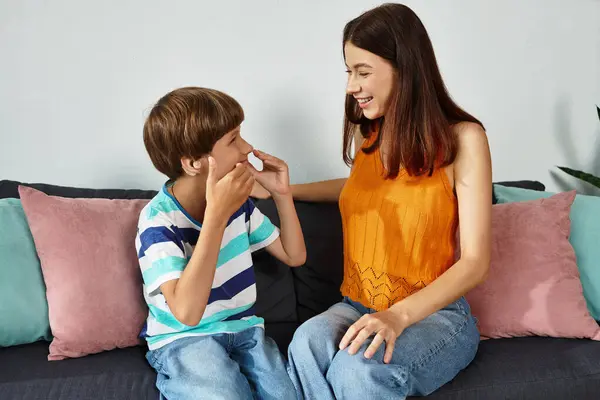A mother smiles as she engages with her son, who has a hearing impairment, at home. — Stock Photo