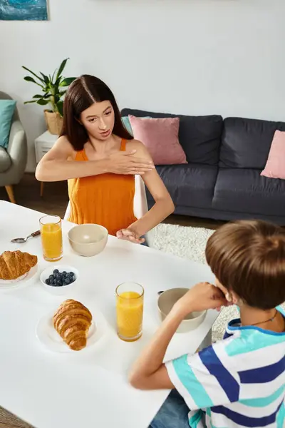 A mother attentively communicates with her son while enjoying breakfast together at home. — Stock Photo
