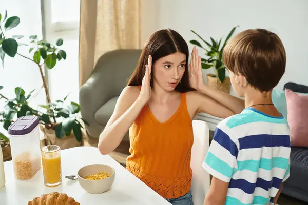 Una madre devota se involucra con su hijo usando lenguaje de señas en su mesa de desayuno. - foto de stock
