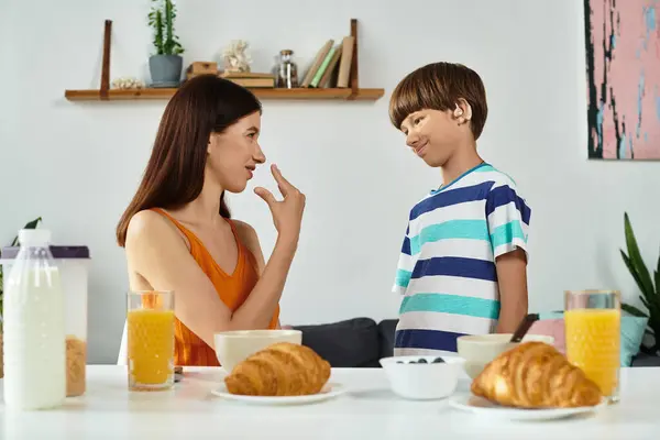 Une mère interagit attentivement avec son fils malentendant pendant le petit déjeuner. — Photo de stock