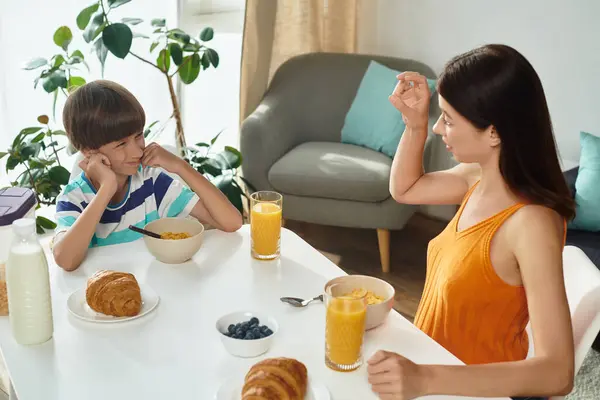 A mother engages her hearing impaired son in joyful conversation over breakfast. — Stock Photo