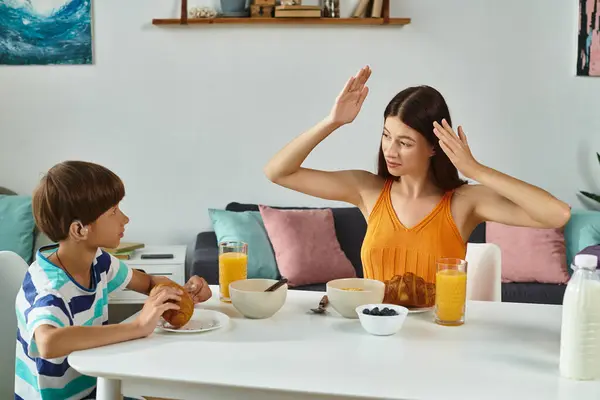 Une mère s'engage avec son fils malentendant lors d'un petit déjeuner chaud dans leur maison. — Photo de stock