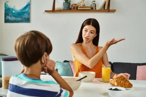 Une mère parle avec son fils malentendant au petit déjeuner dans leur salle à manger confortable. — Photo de stock