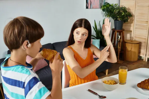 The mother engages her son in learning sign language while they enjoy breakfast together. — Stock Photo
