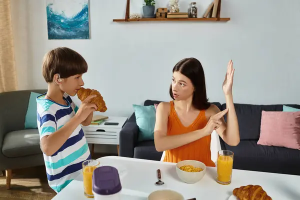 A mother uses sign language to communicate with her son while enjoying breakfast together. — Stock Photo