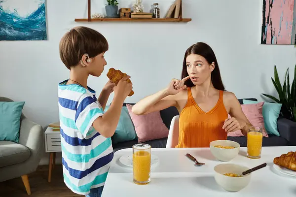 A mother engages with her son, who has a hearing impairment, during breakfast. — Stock Photo