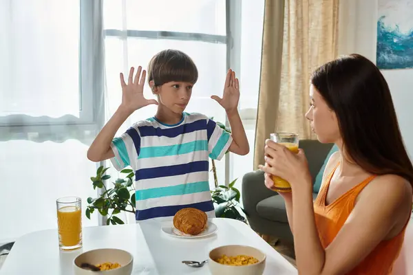 Um menino se comunica com sua mãe, expressando-se enquanto eles compartilham o café da manhã juntos. — Fotografia de Stock