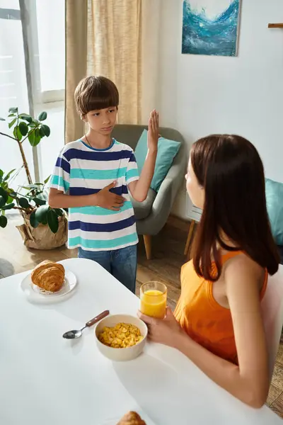 Ein kleiner Junge kommuniziert mit seiner Mutter beim Frühstück und zeigt eine herzliche Verbindung. — Stockfoto