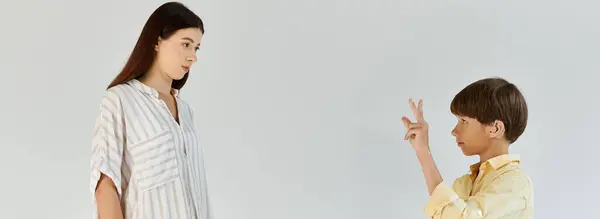 A mother observes her son with hearing impairment as he communicates using sign language. — Stock Photo