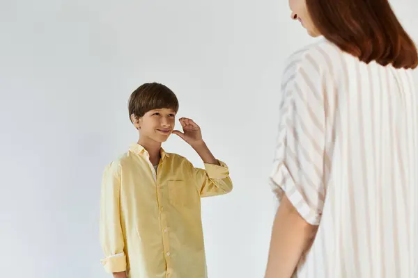 A happy little boy with hearing impairment smiles and interacts with his caring mother. — Stock Photo
