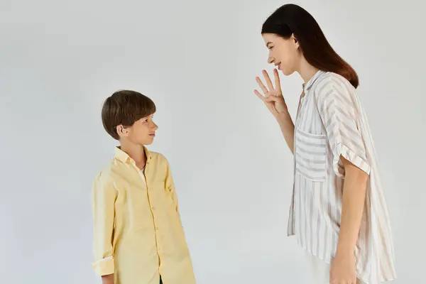 In a bright space, a mother joyfully signs with her little boy, highlighting their bond. — Stock Photo