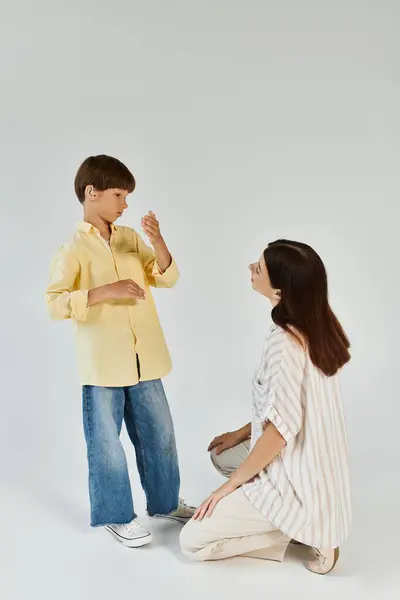 A young boy with hearing impairment enjoys a meaningful conversation with his caring mother. — Stock Photo