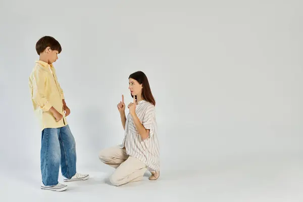 A caring mother kneels down to engage with her son who has a hearing impairment. — Stock Photo