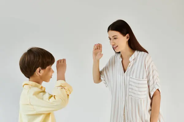 Un ragazzo con disabilità uditiva si impegna in un momento gioioso con sua madre, usando il linguaggio dei segni.. — Foto stock