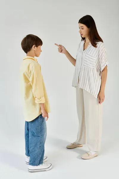 Um menino com deficiência auditiva está diante de sua mãe, envolvido em uma discussão carinhosa. — Fotografia de Stock