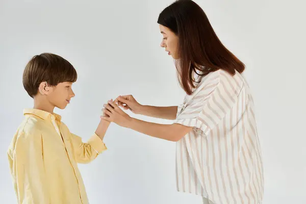 A mother lovingly assists her young son with hearing impairment in an everyday activity. — Stock Photo