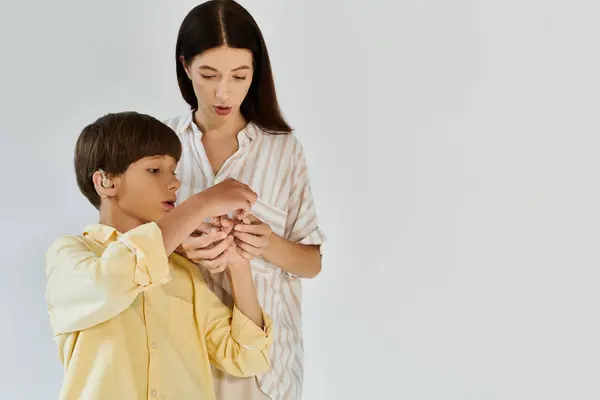 A little boy eagerly examines a device while his attentive mother guides him in a bright setting. — Stock Photo