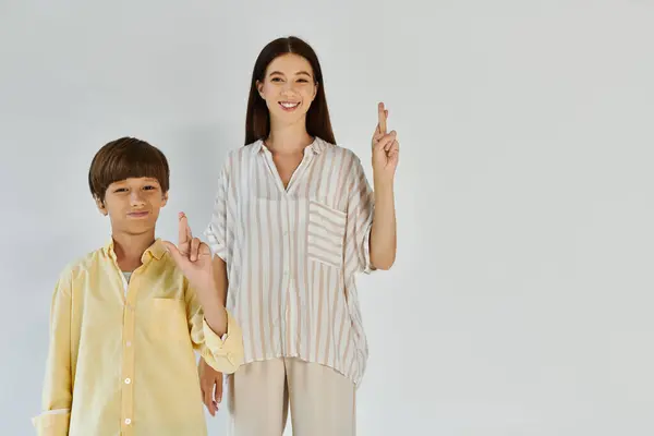 A mother and her young son show their bond through a hopeful gesture in a light filled space. — Stock Photo