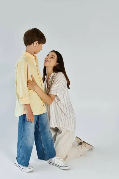 A mother interacts playfully with her son who has a hearing impairment, radiating joy and love. — Stock Photo