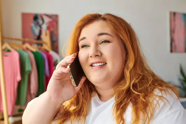 Женщина plus size с красивыми кудрявыми волосами весело болтает по телефону в бутике. — стоковое фото