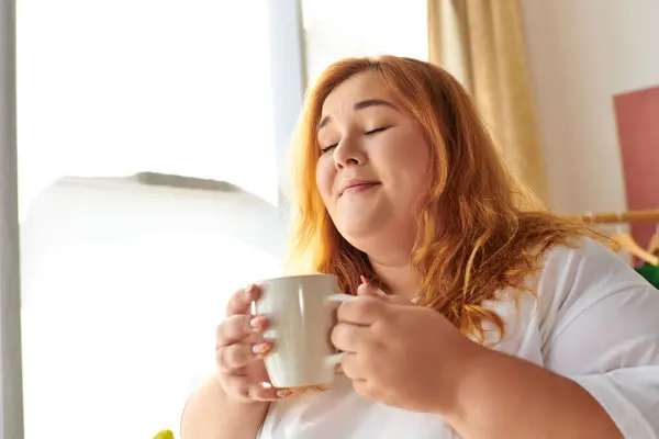 A plus size woman enjoys her tea, radiating comfort in a cozy moment. — Stock Photo