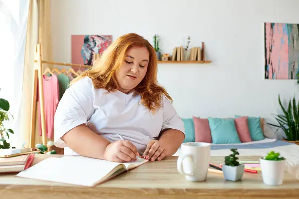 Una bella donna plus size è impegnata nella scrittura al suo spazio di lavoro elegante e luminoso. — Foto stock