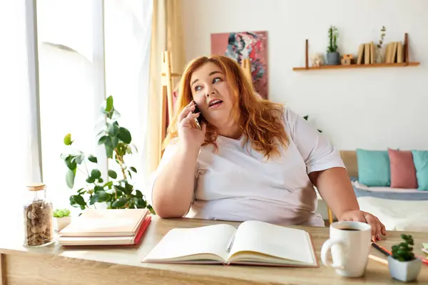A plus size woman chats animatedly on the phone at a cozy wooden table. — Stock Photo