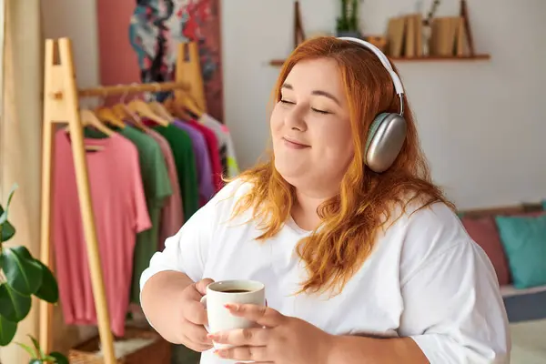 The woman enjoys a peaceful moment, sipping tea while listening to music in her cozy space. — Stock Photo
