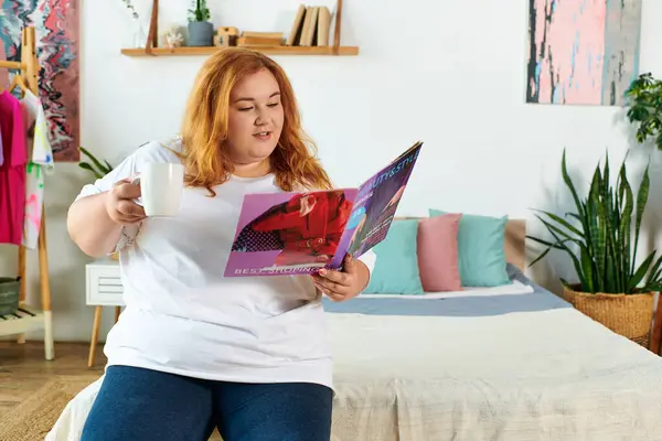 A beautiful plus size woman relaxes with a magazine and tea in a vibrant, inviting space. — Stock Photo