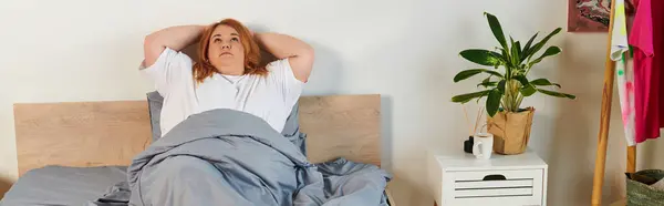 A surprised plus size woman sits upright in soft bedding. — Stock Photo