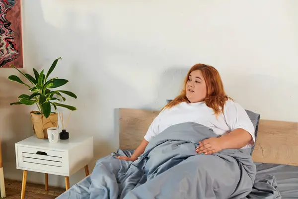 A plus size woman relaxes in her cozy bedroom, enjoying a peaceful morning. — Stock Photo