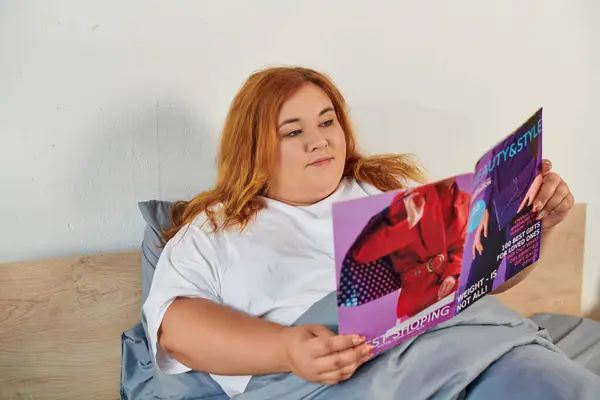 В тихом месте женщина plus size расслабляется, читая последние модные тенденции. — стоковое фото