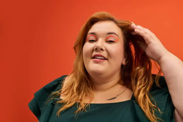 A plus size woman joyfully poses, showcasing her stunning features with a bright orange background. — Stock Photo
