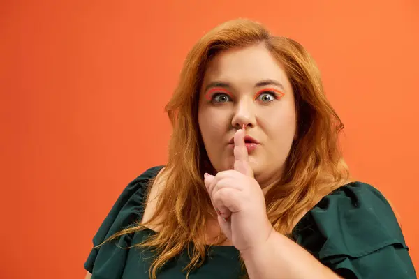 A beautiful plus size woman playfully gestures for silence against a bright backdrop. — Stock Photo
