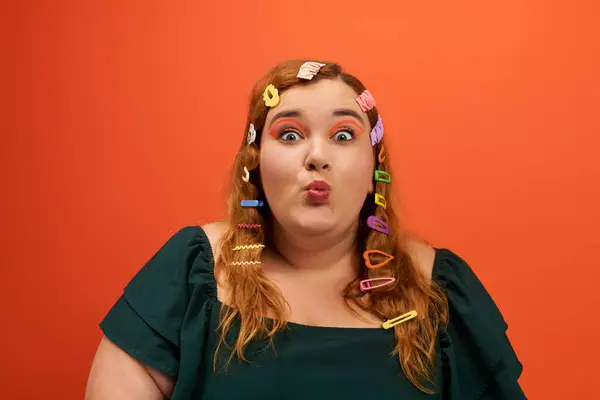 The beautiful plus size woman with colorful hair clips on her curls makes a playful expression. — Stock Photo