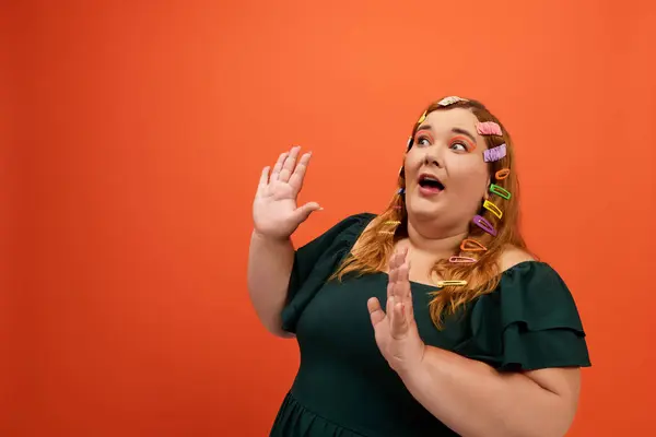 La donna plus size reagisce gioiosamente, ostentando le sue clip di capelli colorati e vestito vibrante. — Foto stock