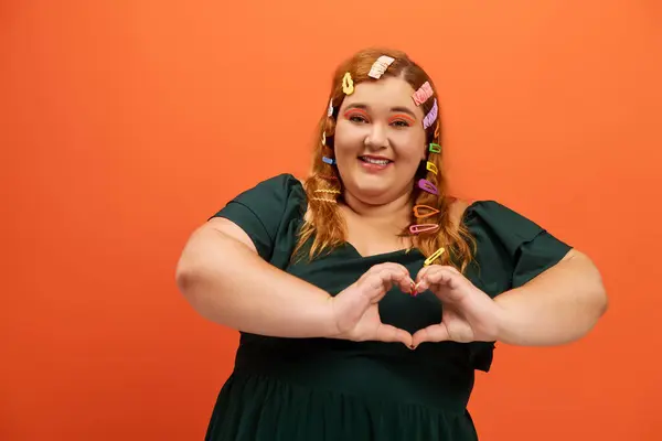 Eine fröhliche Plus-Size-Frau macht mit ihren Händen ein Herzzeichen und strahlt Positivität und Charme aus. — Stockfoto