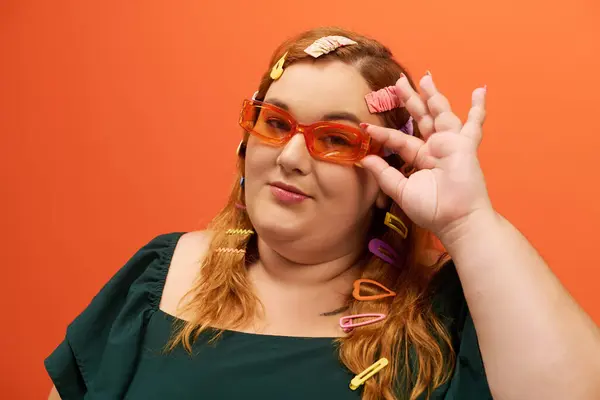 Mit bunten Clips im Haar umarmt eine selbstbewusste Frau ihre Schönheit in kühner Brille. — Stock Photo