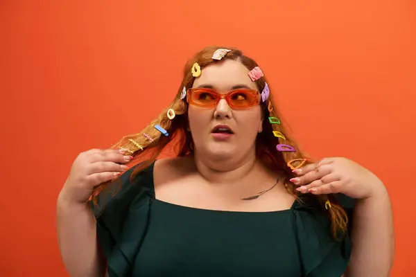 Dressed in a stylish outfit, a plus size woman playfully styles her colorful hair accessories. — Stock Photo