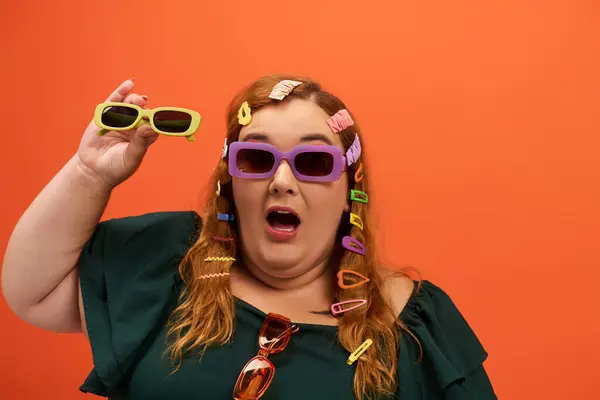 A plus size woman joyfully showcases her colorful style with playful accessories and sunglasses. — Stock Photo