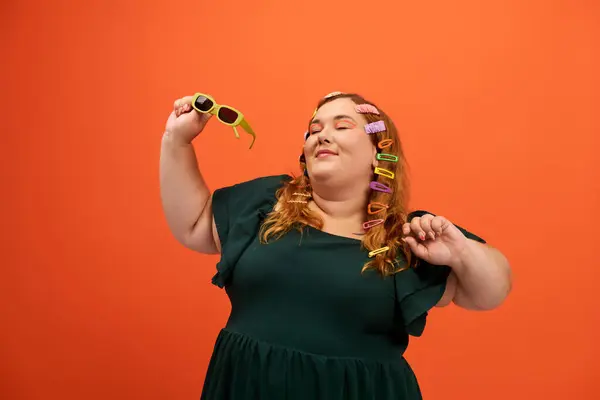 A confident plus size woman dances happily, showcasing her unique style with vibrant accessories. — Stock Photo