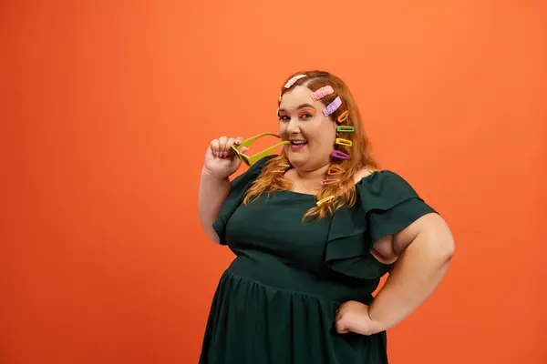 Smiling woman with hair rollers exudes playfulness against a vibrant backdrop. — Stock Photo