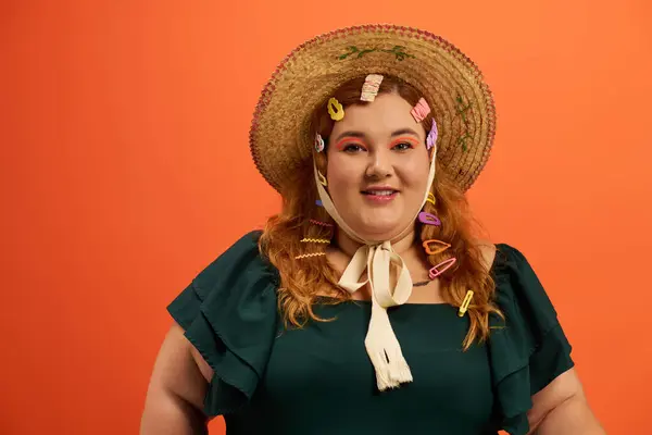 Una mujer alegre de talla grande posa con pinzas coloridas en el pelo y un sombrero de ala ancha. — Stock Photo