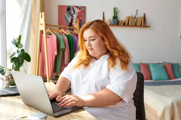 A plus size woman focuses on her laptop in a vibrant, inviting home. — Stock Photo