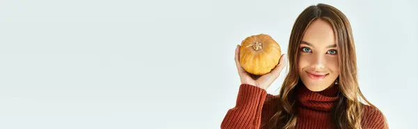 A beautiful woman dressed in a Halloween costume holds a pumpkin, capturing the autumn spirit. — Stock Photo