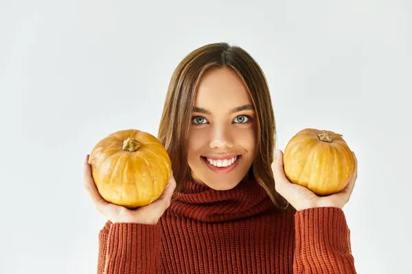 This cheerful young woman embraces the spirit of Halloween by holding two vibrant pumpkins. — Stock Photo