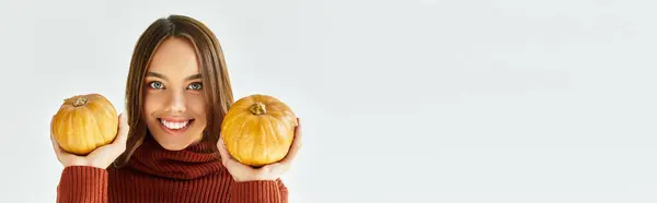 A beautiful young woman dressed for Halloween happily holds two pumpkins, embracing festive fun. — Stock Photo