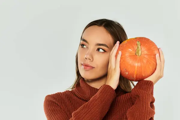 A young woman dressed in festive Halloween attire holds a pumpkin while enjoying the celebration. — Stock Photo