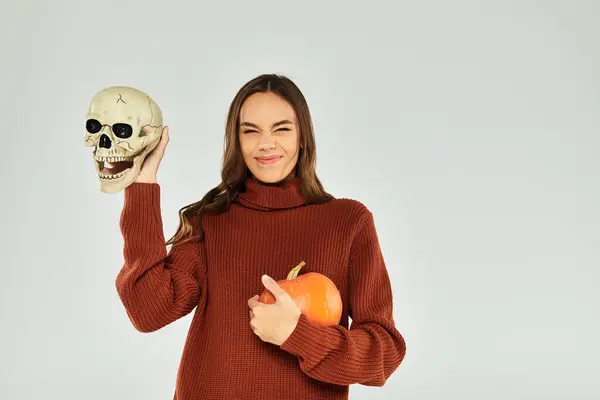 Una giovane bella donna abbraccia lo spirito di Halloween tenendo un teschio e una zucca con un sorriso. — Foto stock